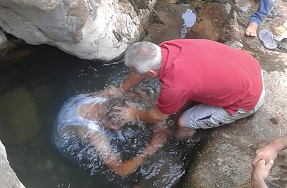 A man baptizing another man in the river
