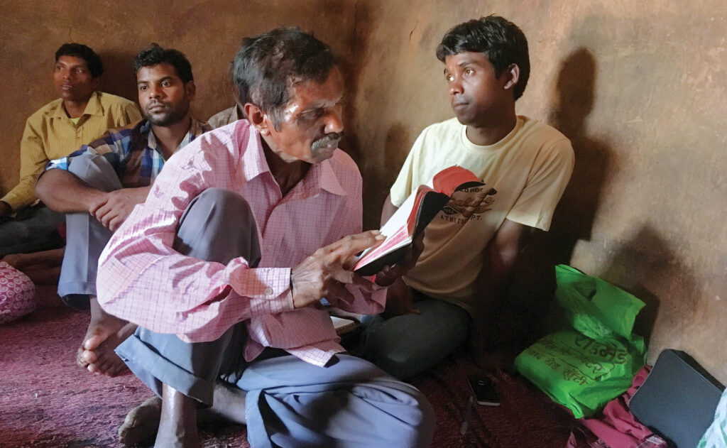 An Indian man sits reading the Bible to kids in church