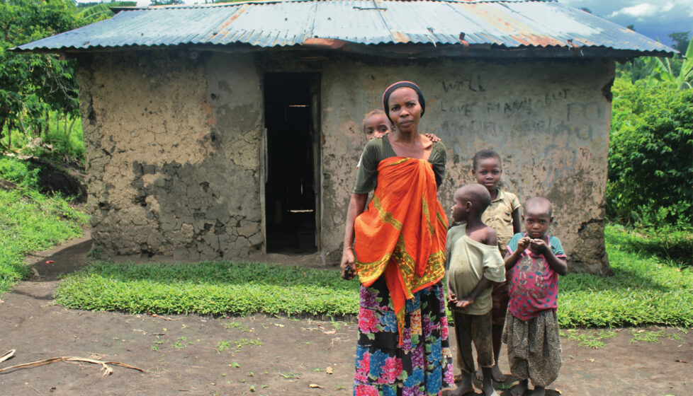 A woman standing outside in front of her house with her four children