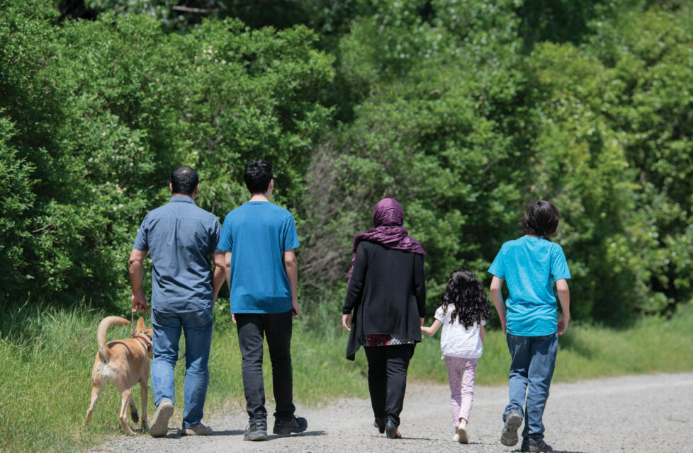 Iranian family of believers walking down a road together with a dog