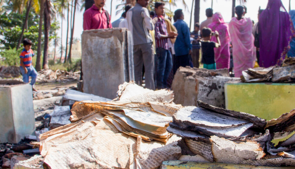 A group of people gathered looking at a burned Bible