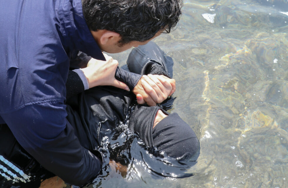 man baptizes woman in river