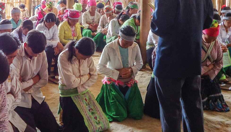 A Man standing in front of his congregation while they pray