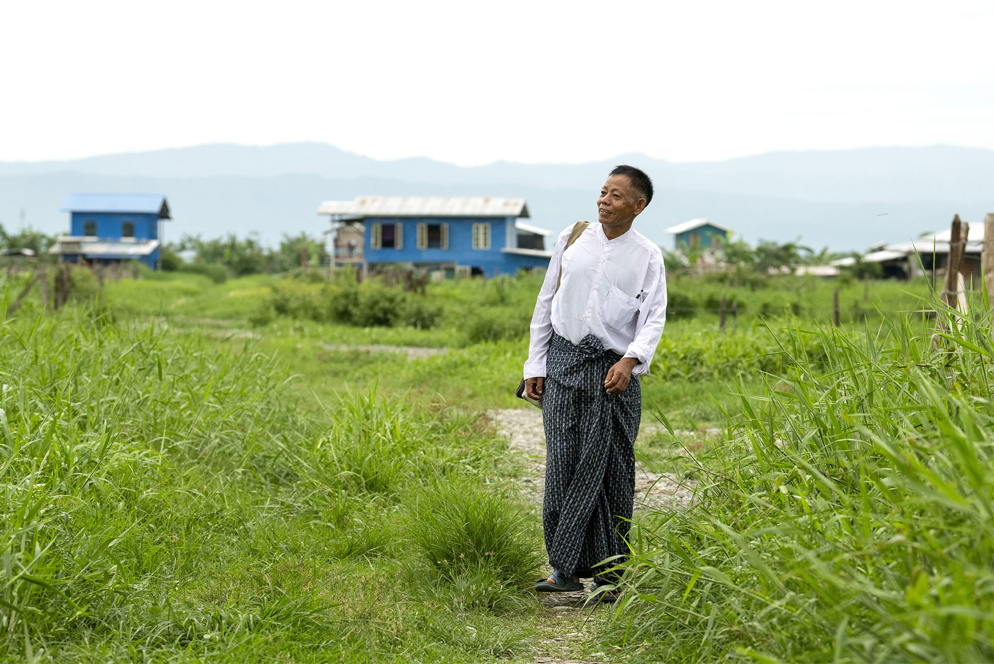 Man walking a grassy trail, looking hopeful