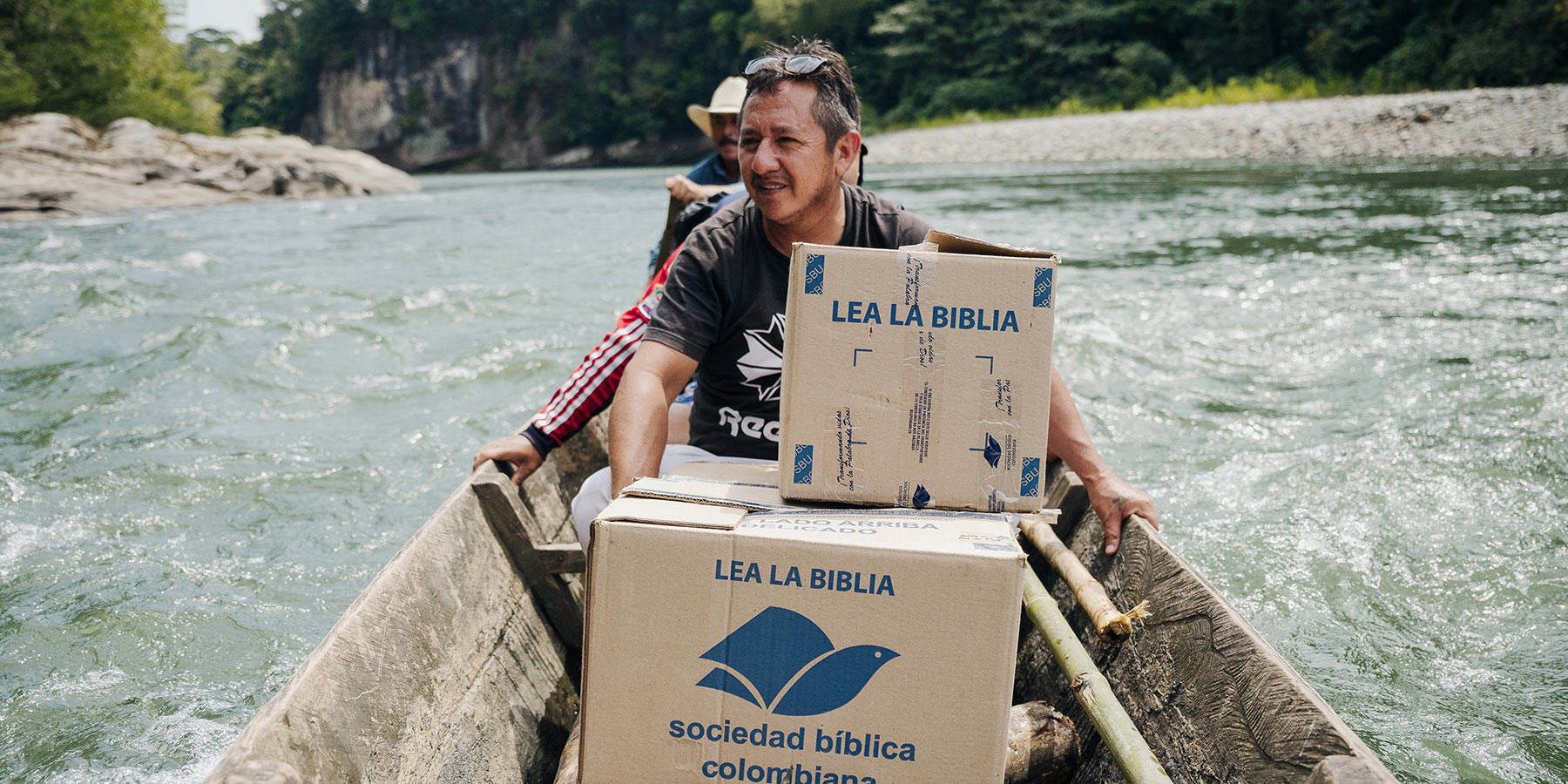 People in canoe transporting boxes of Bibles.