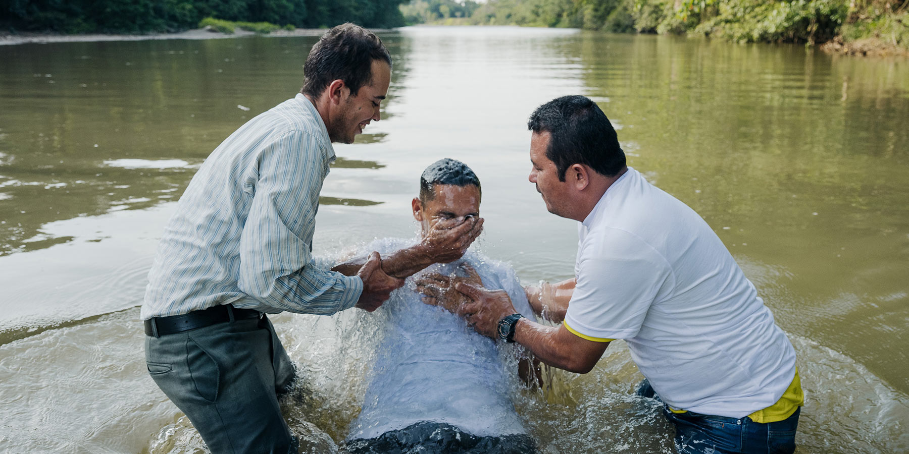 Person being baptized in a river.