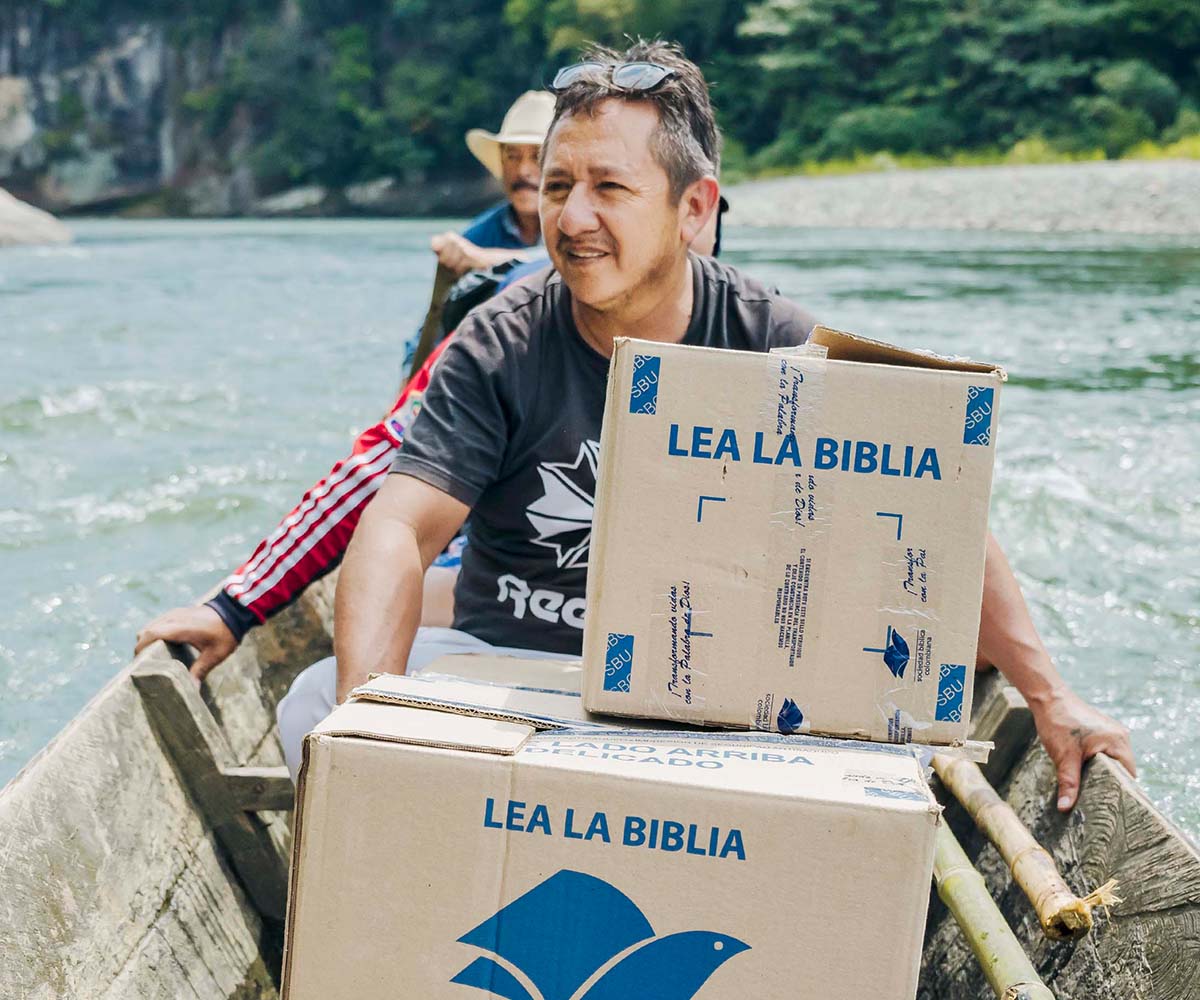 People in canoe transporting boxes of Bibles.