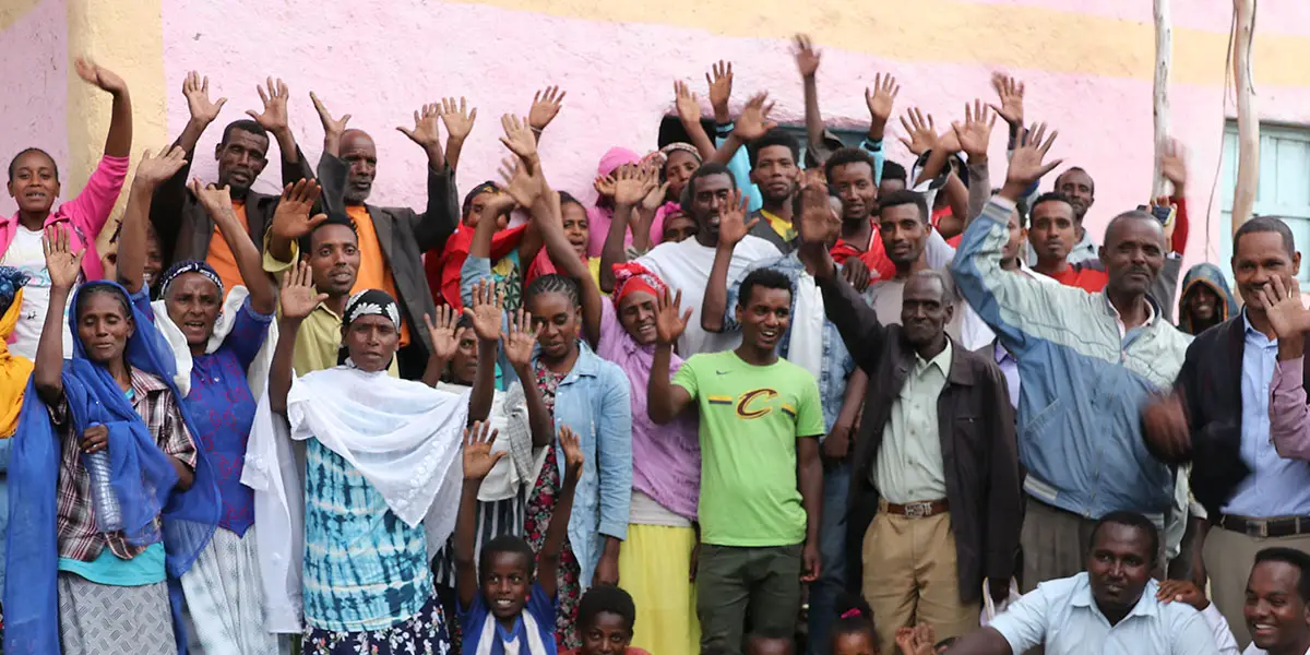 Crowd in front of pink wall waving