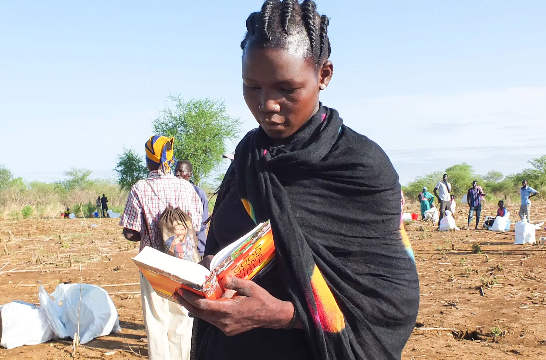 Sudanese woman in black dress reading a Bible