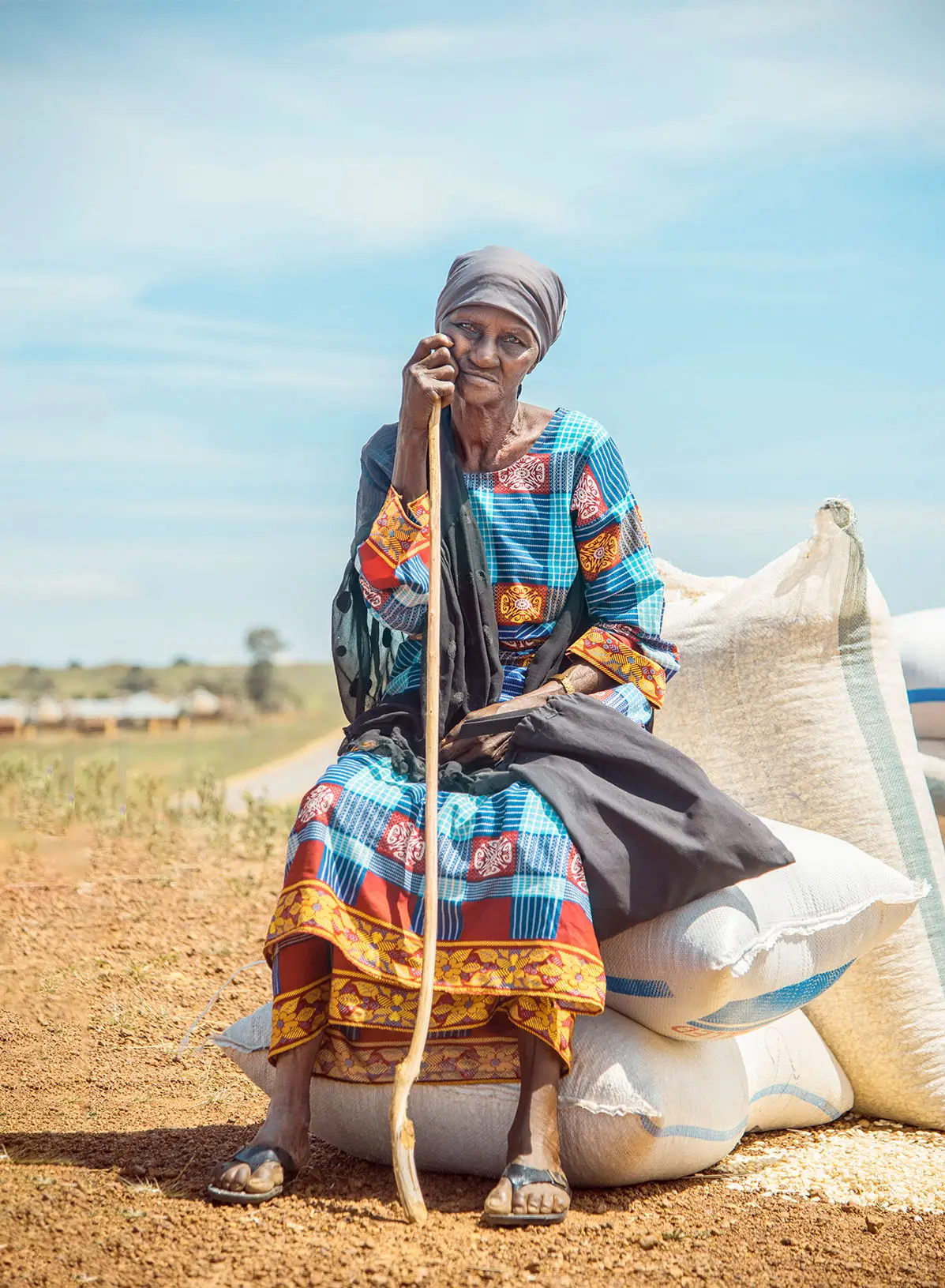 Elderly woman sitting on bags of rice