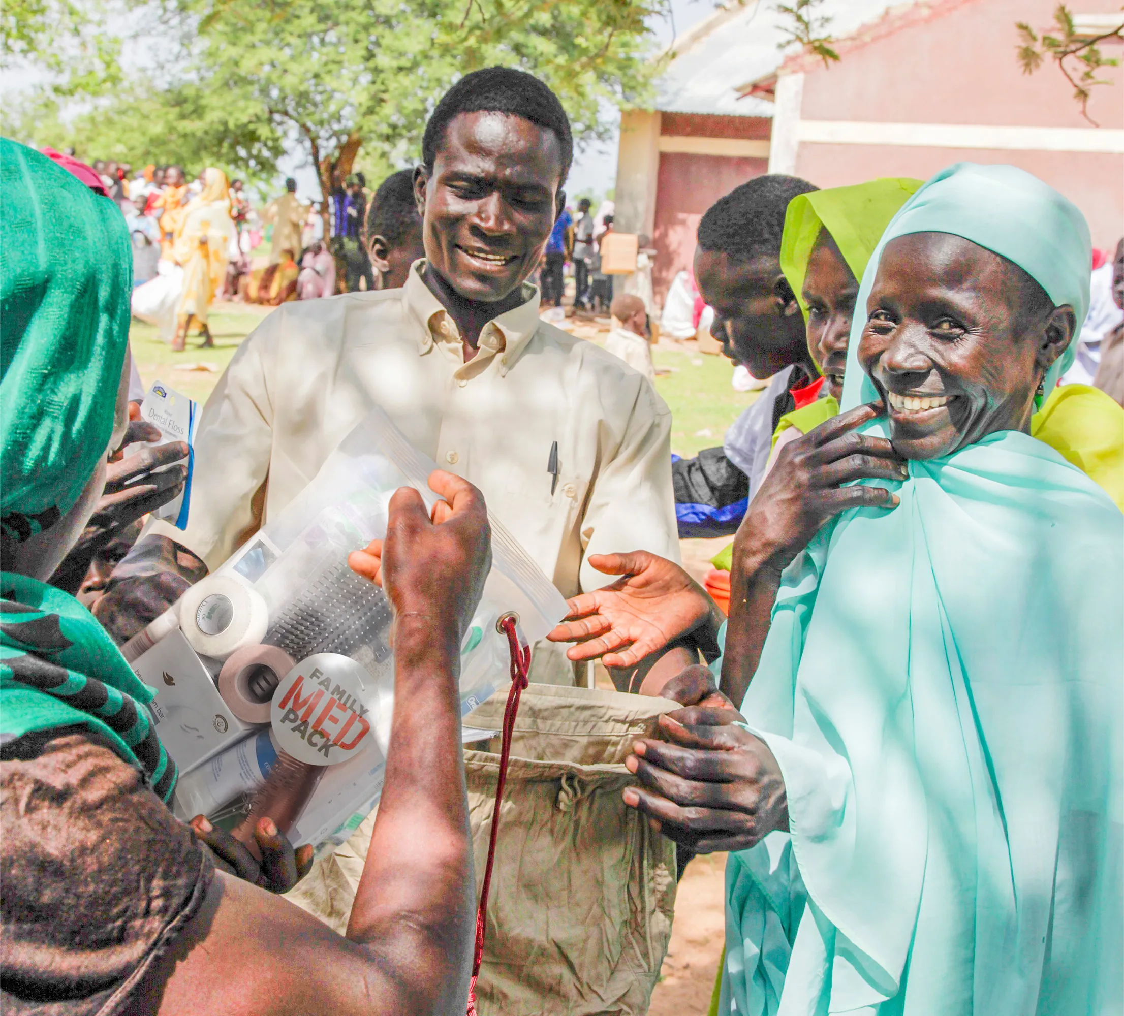 Group of people smiling as they receive family med packs