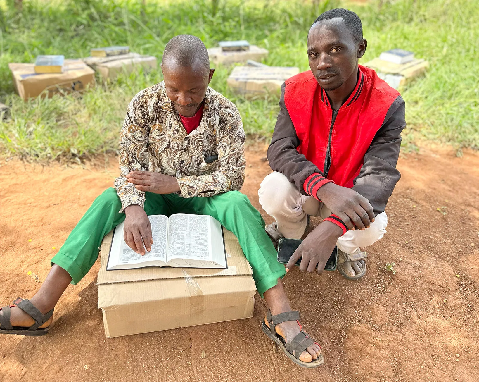 Two men reading Bibles on a box of Bibles