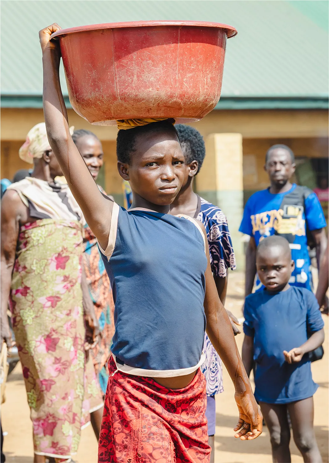 Child carrying water bucket on their head