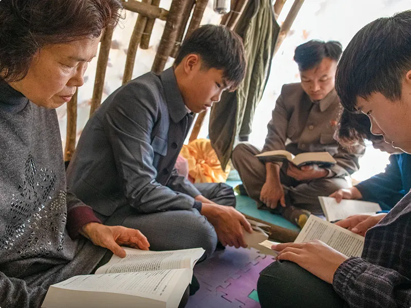 Group of people sitting on a floor with Bibles