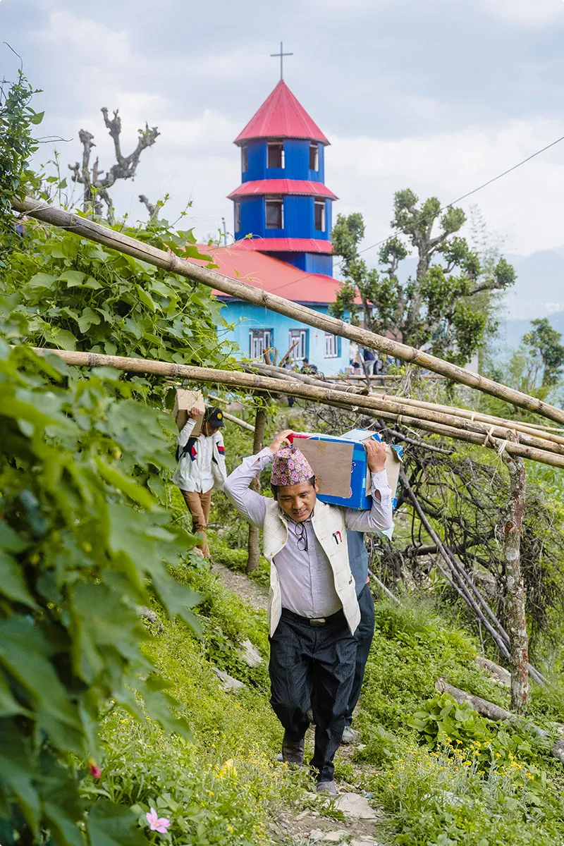 People carrying boxes of Bibles down a trail