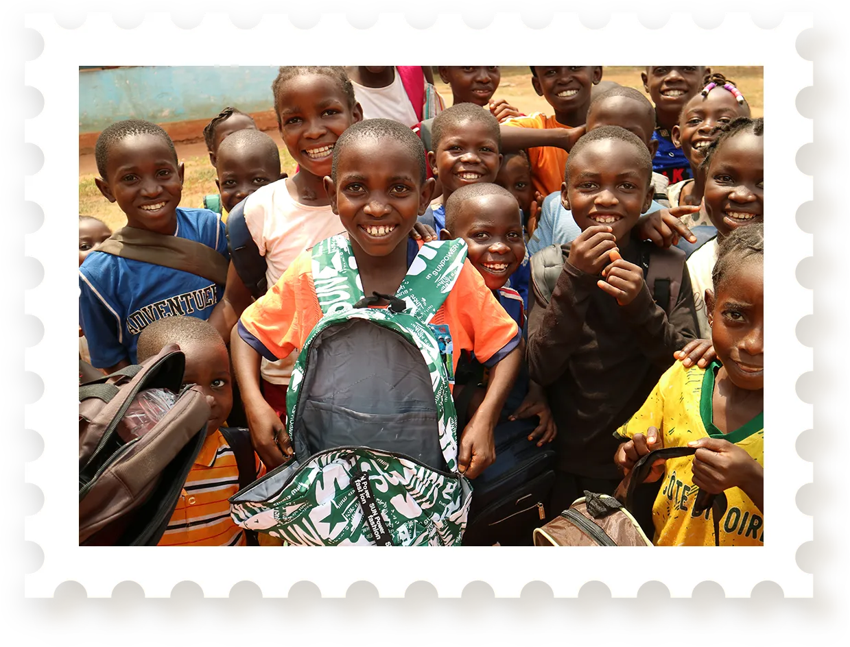 Group of children smiling and holding backpacks