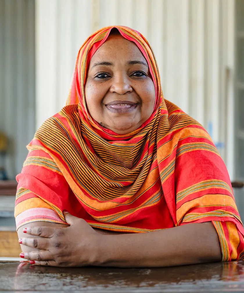 Woman with orange clothes smiling at a table