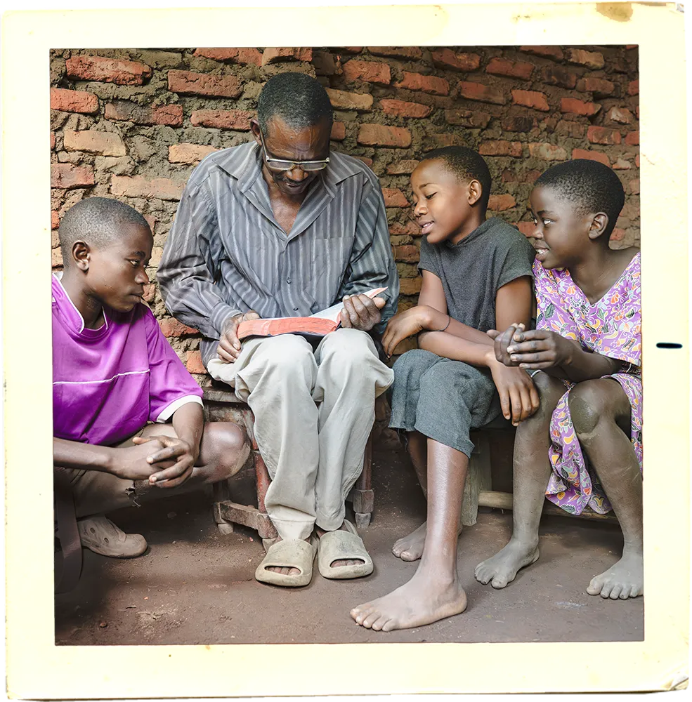 Man reading a Bible to three boys