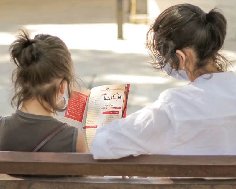 Two people sitting on a bench reading
