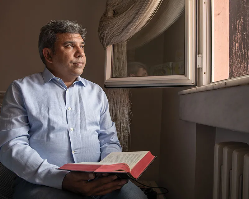 Man with Bible looking out of window