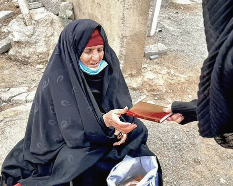 Elderly woman receiving a Bible from worker