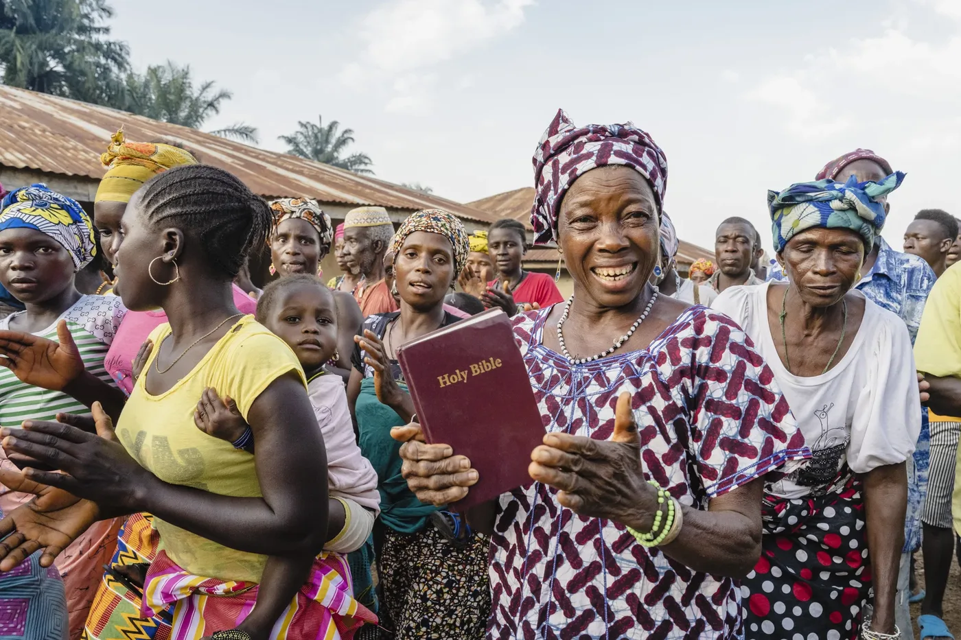 A smiling woman holding her Bible among fellow believers