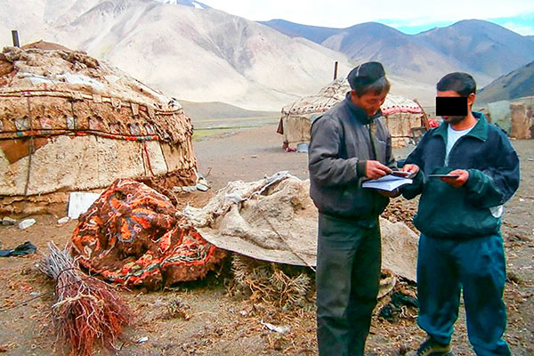 Two men reading a bible outside a yurt