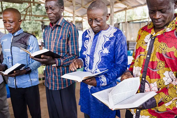 Four men standing together and reading Bibles