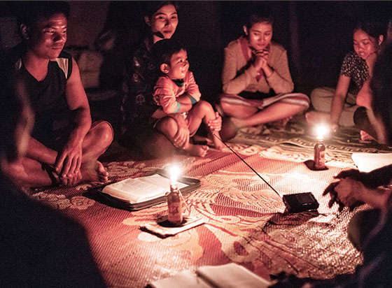 People reading in a dark, candlelit room