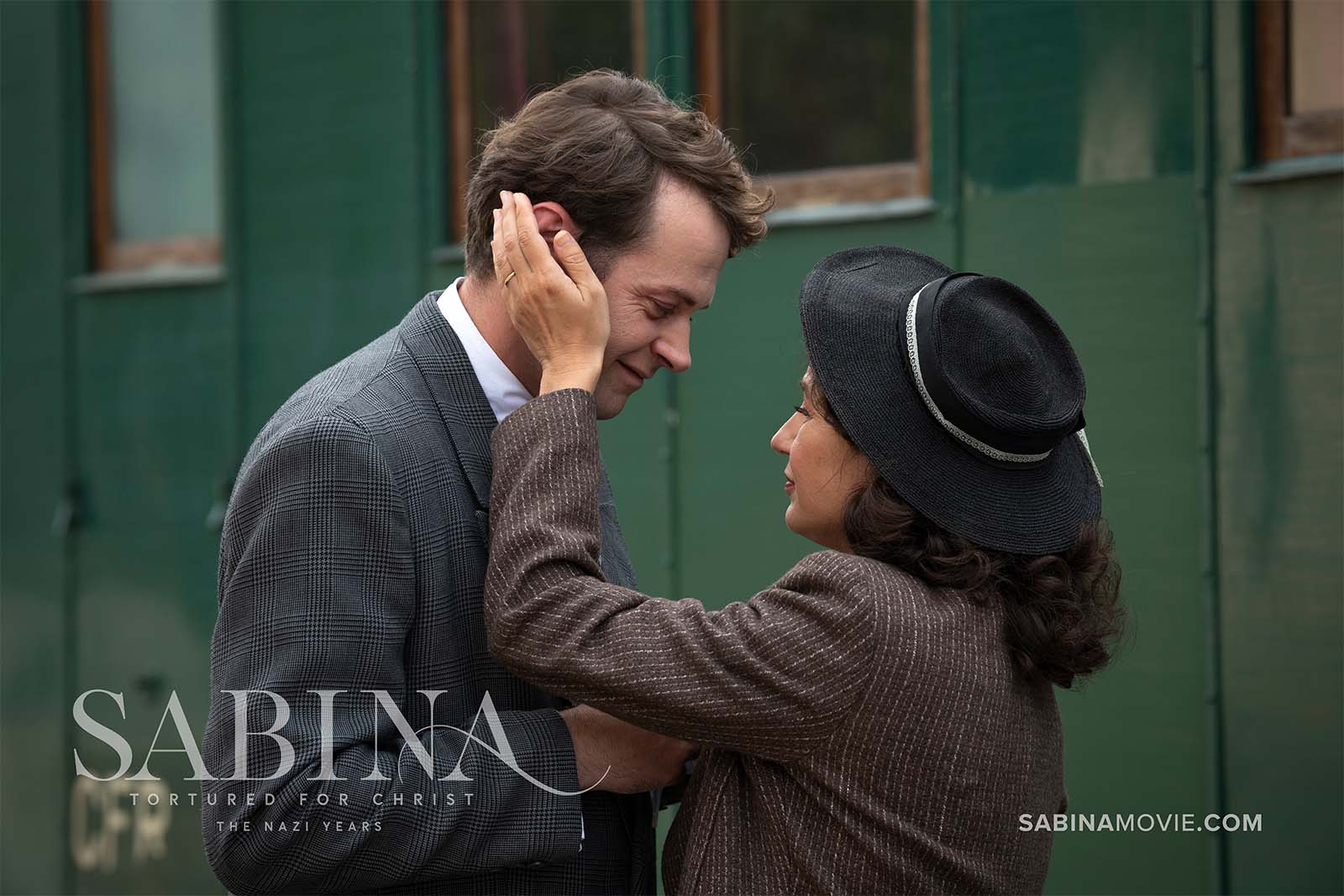 Sabina embracing richard in front of a train.