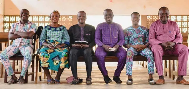 Group sitting on a bench in front of a church