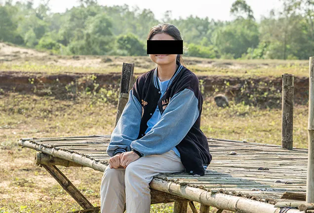 Woman sitting on platform with face masked for confidentiality