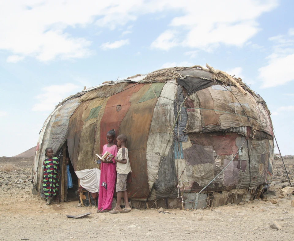 Children reading together outside their home