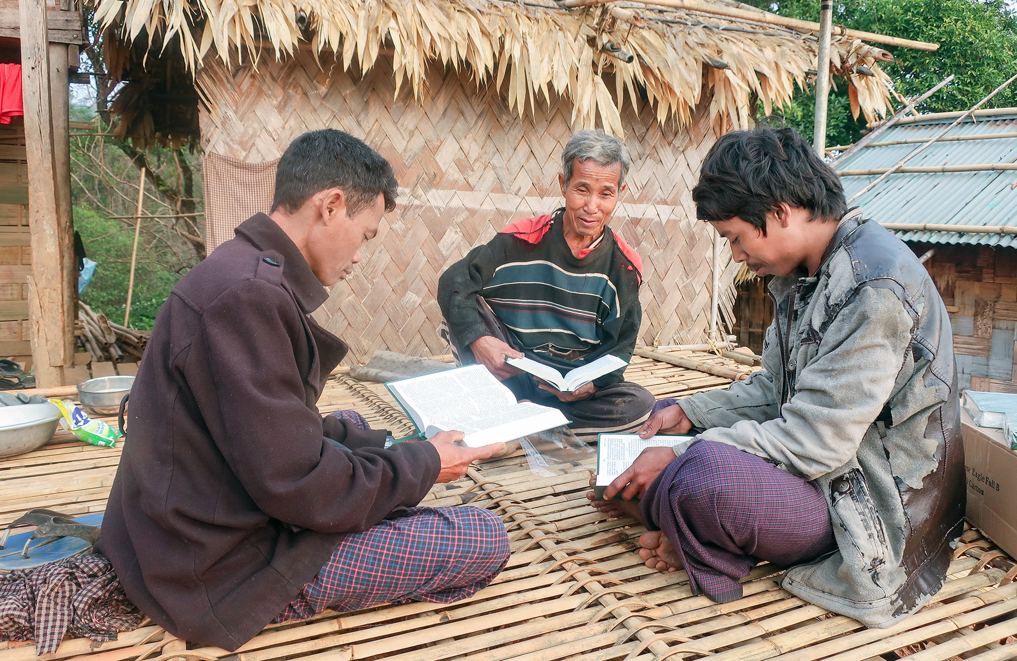 Three men sitting and reading Bibles