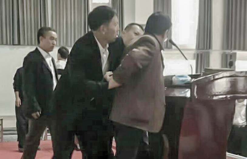 Man at podium being arrested