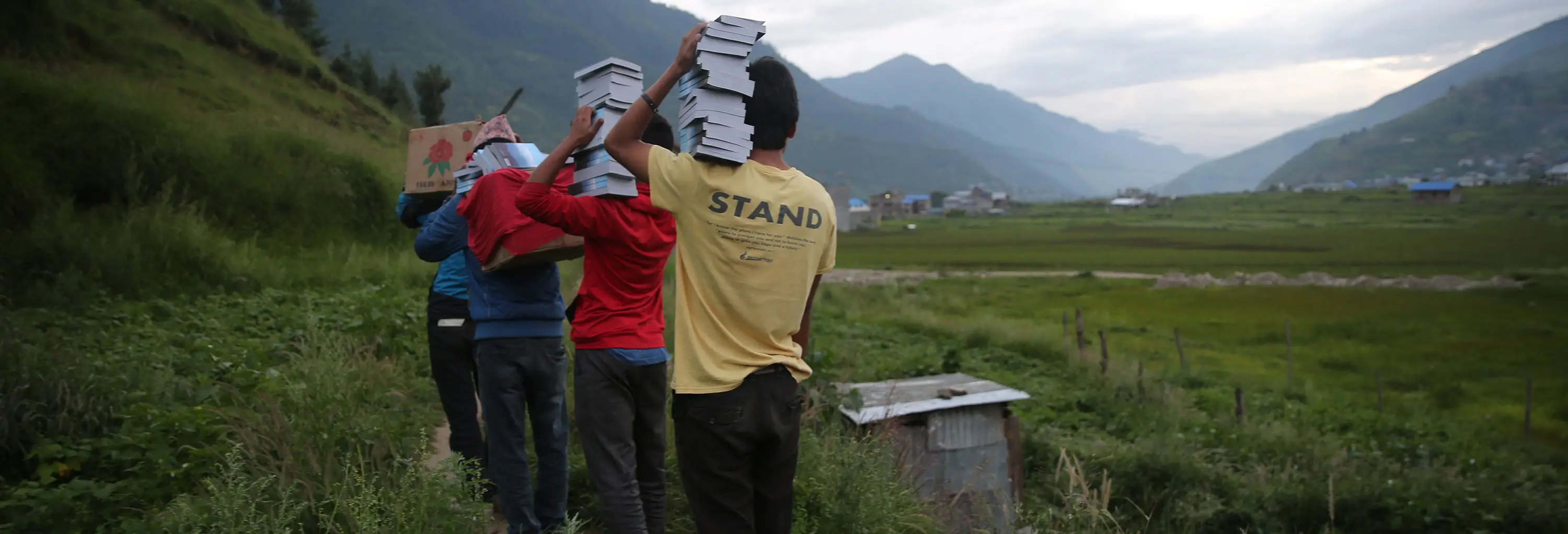 Group of people carrying stacks of Bibles through valley
