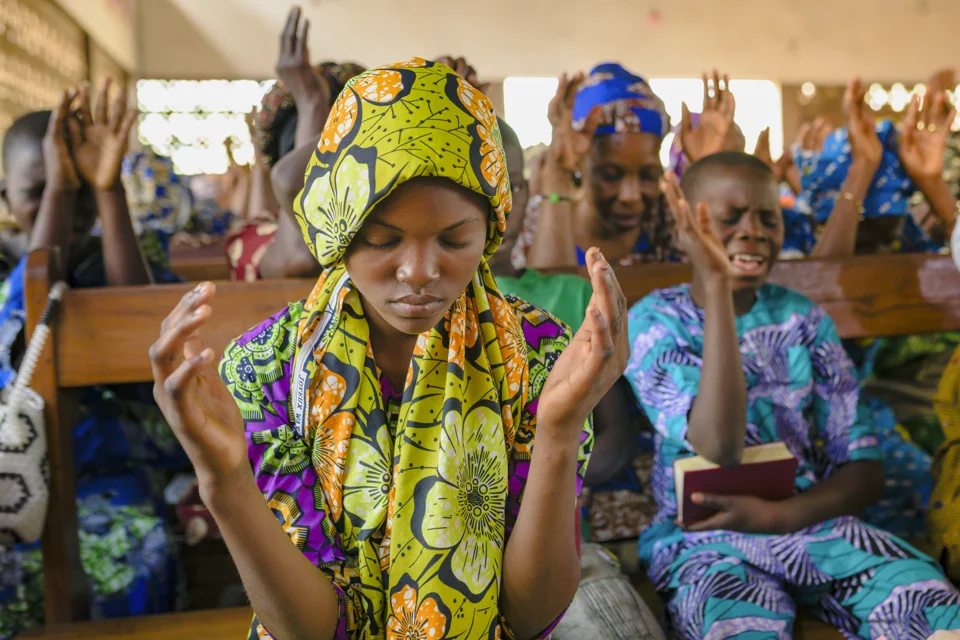Women praying together with raised hands