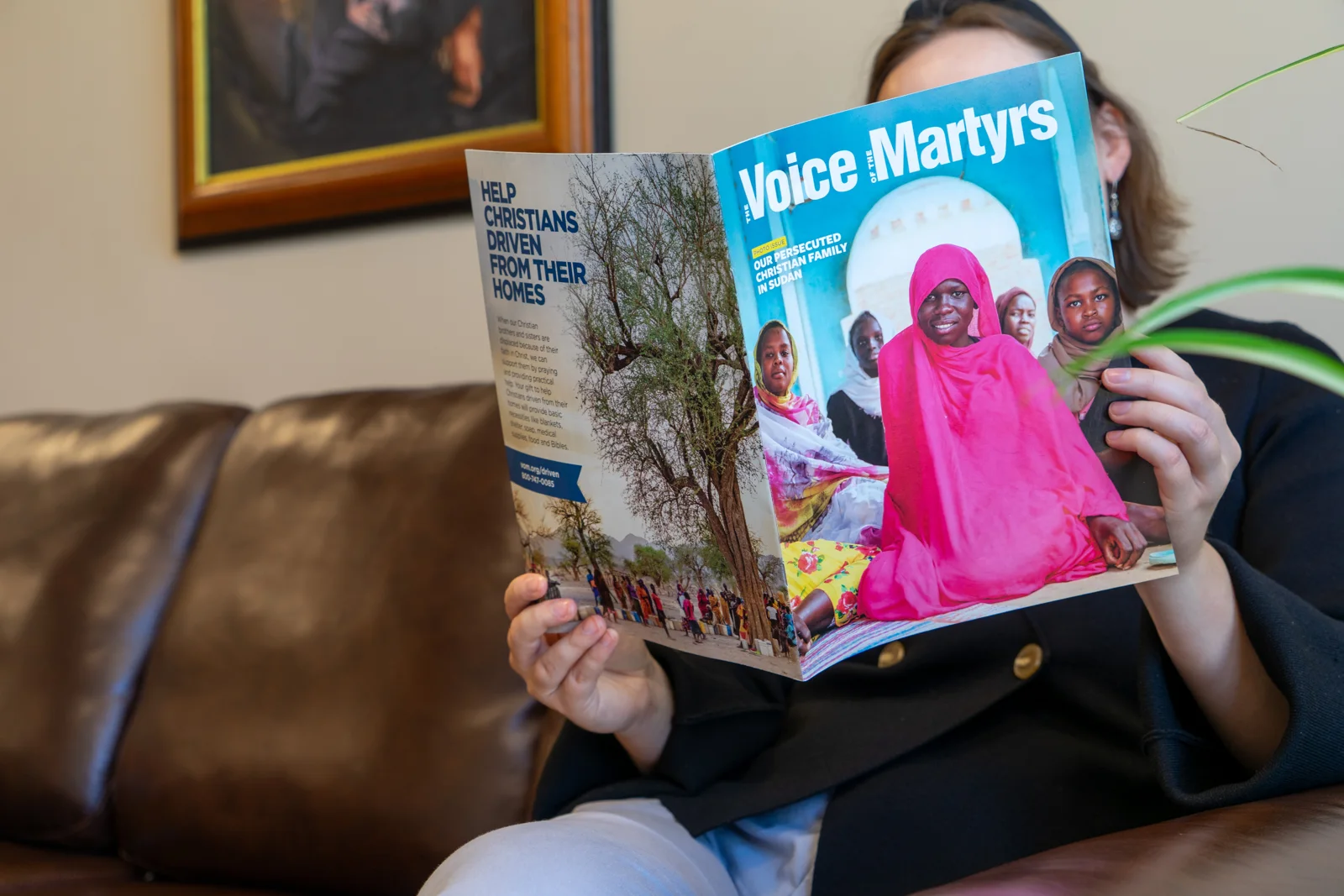 A reader holding her printed copy of The Voice of the Martyrs magazine