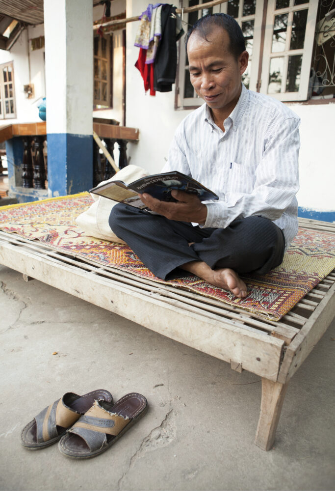 a man sits on a wood platform and reads his bible 