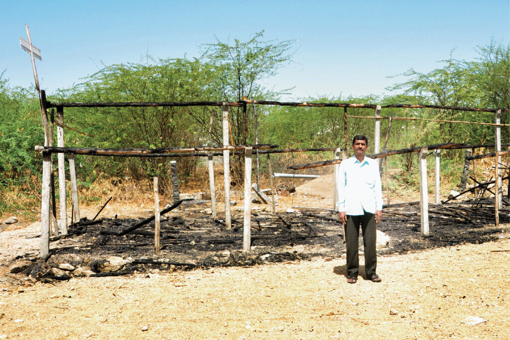 man stands in front of a burned building 