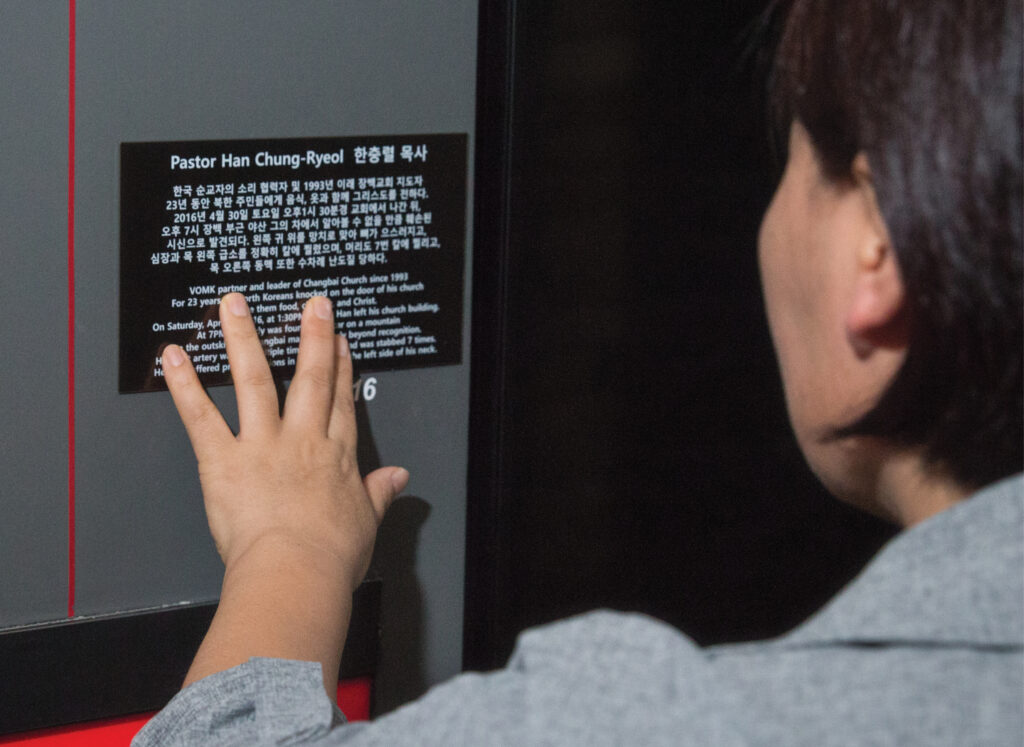 Woman reading a plaque with the story of Pastor Han on it 