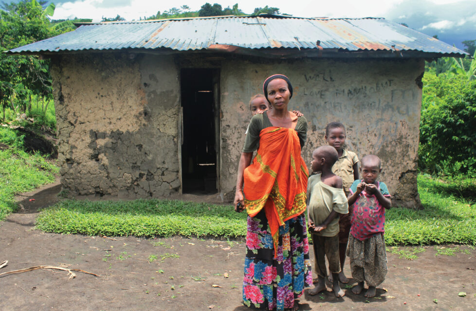 A woman standing outside in front of her house with her four children