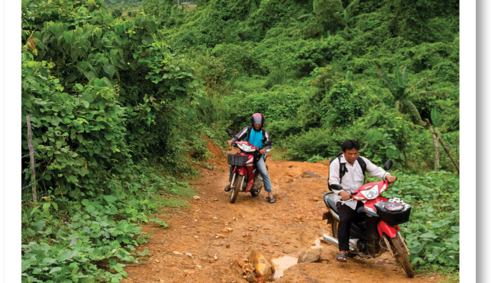 Two men riding motorbikes up a hill