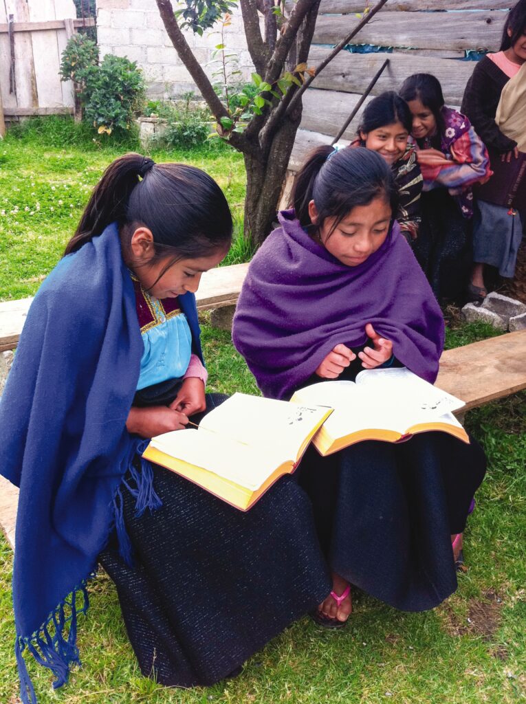 two girls sitting outside reading their bibles 