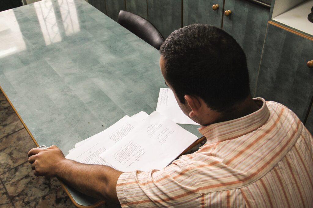 a man sits at a table and reads papers of the bible