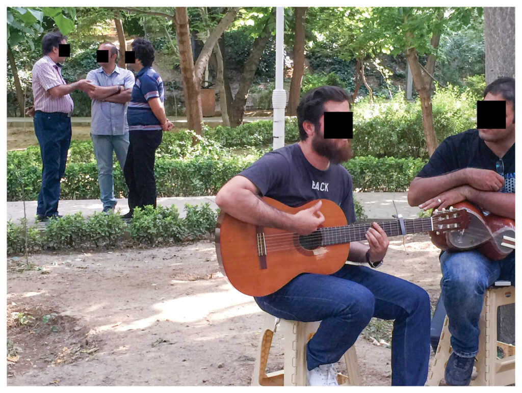 a man plays his guitar outside to a group of people 