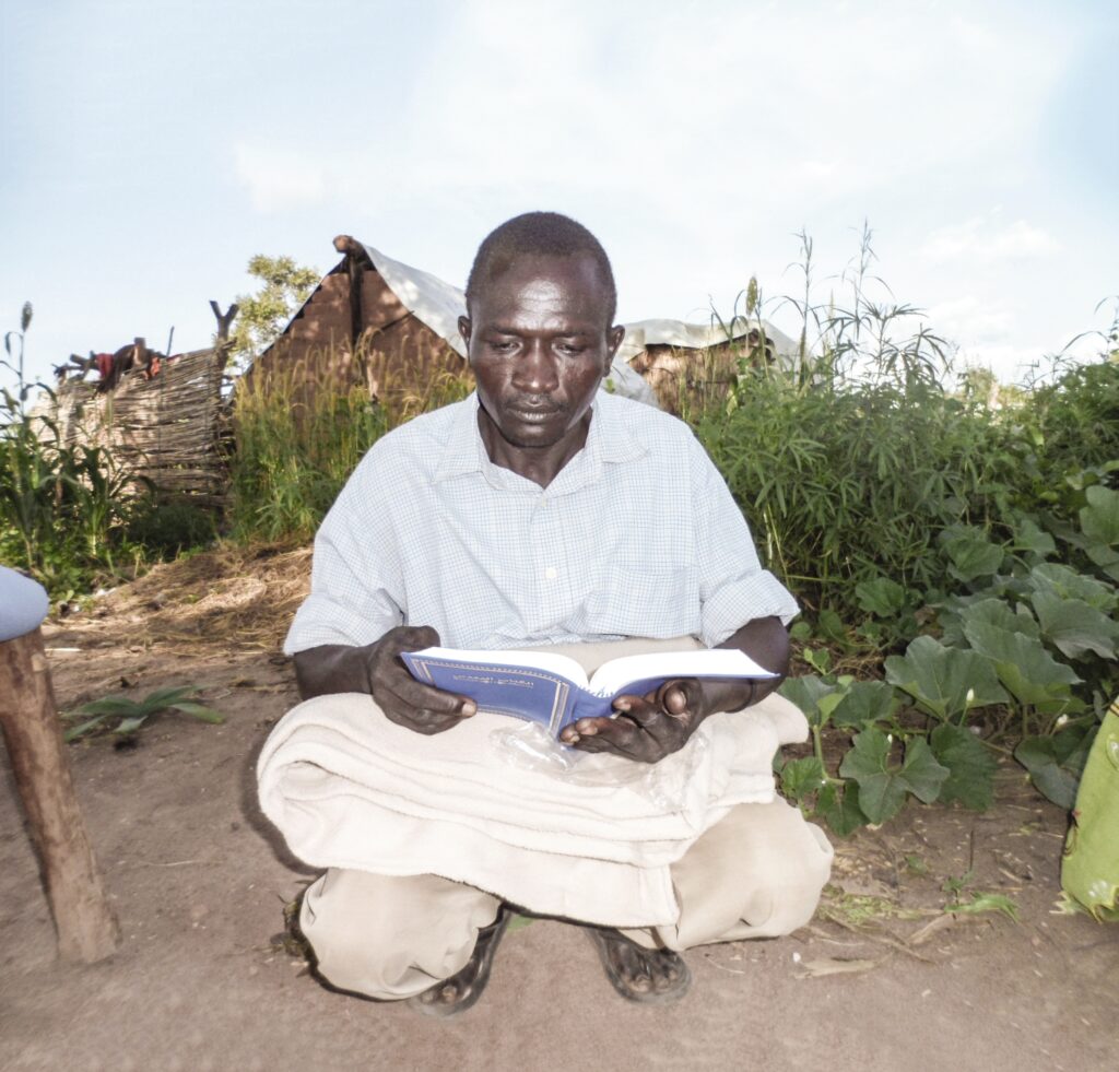 a man sits outside reading his bible