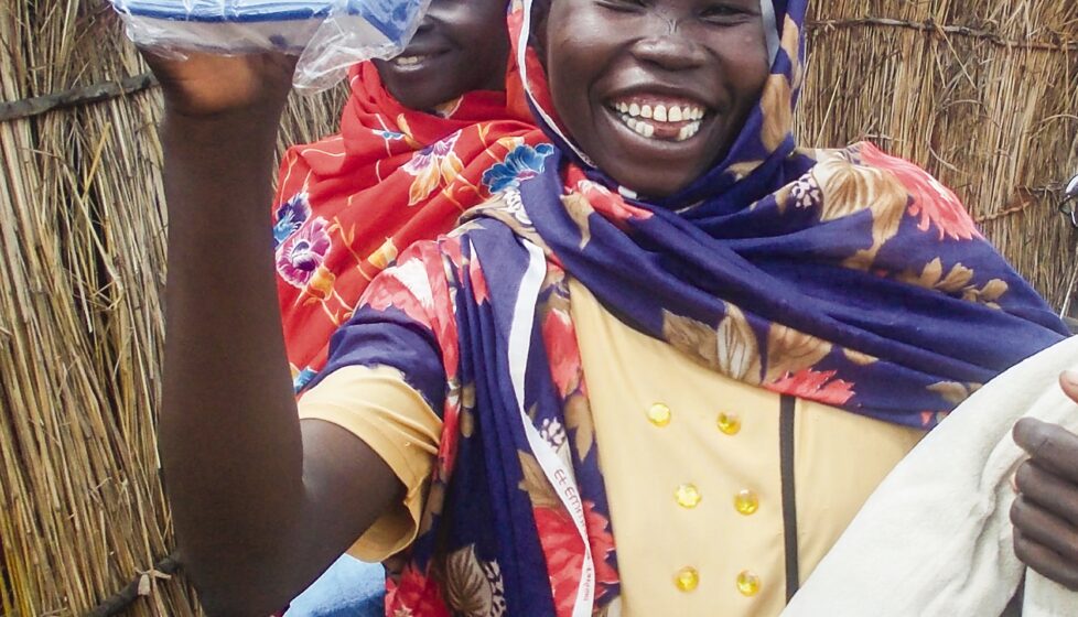 a woman smiles and holds up her new bible