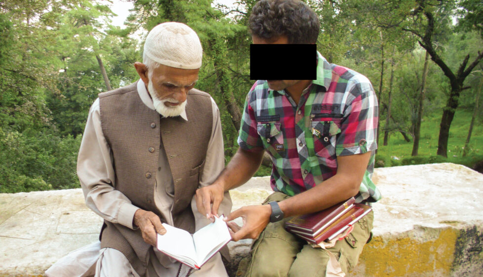 A young man sits and shares the gospel with an older man