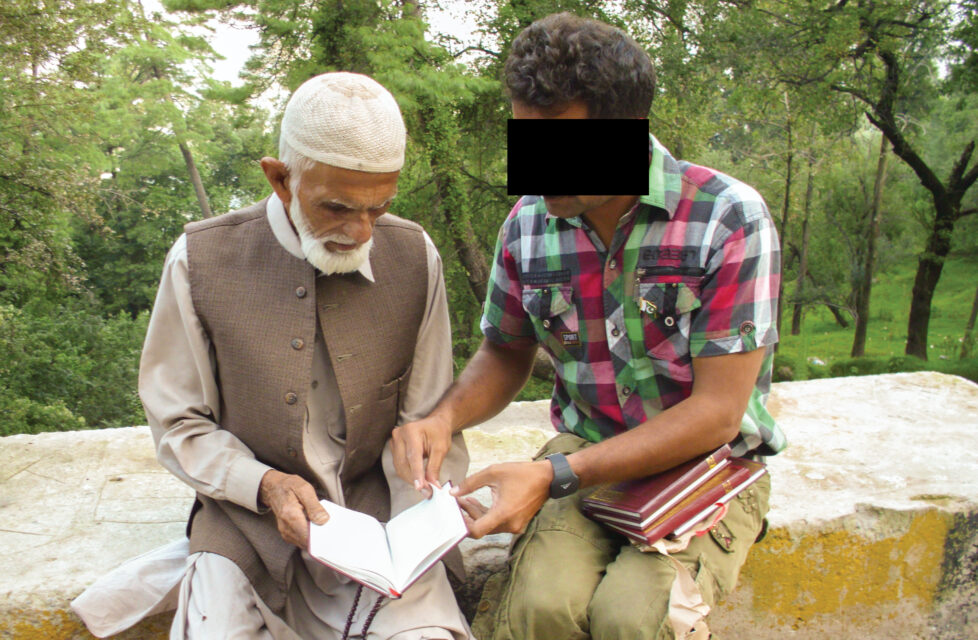 A young man sits and shares the gospel with an older man